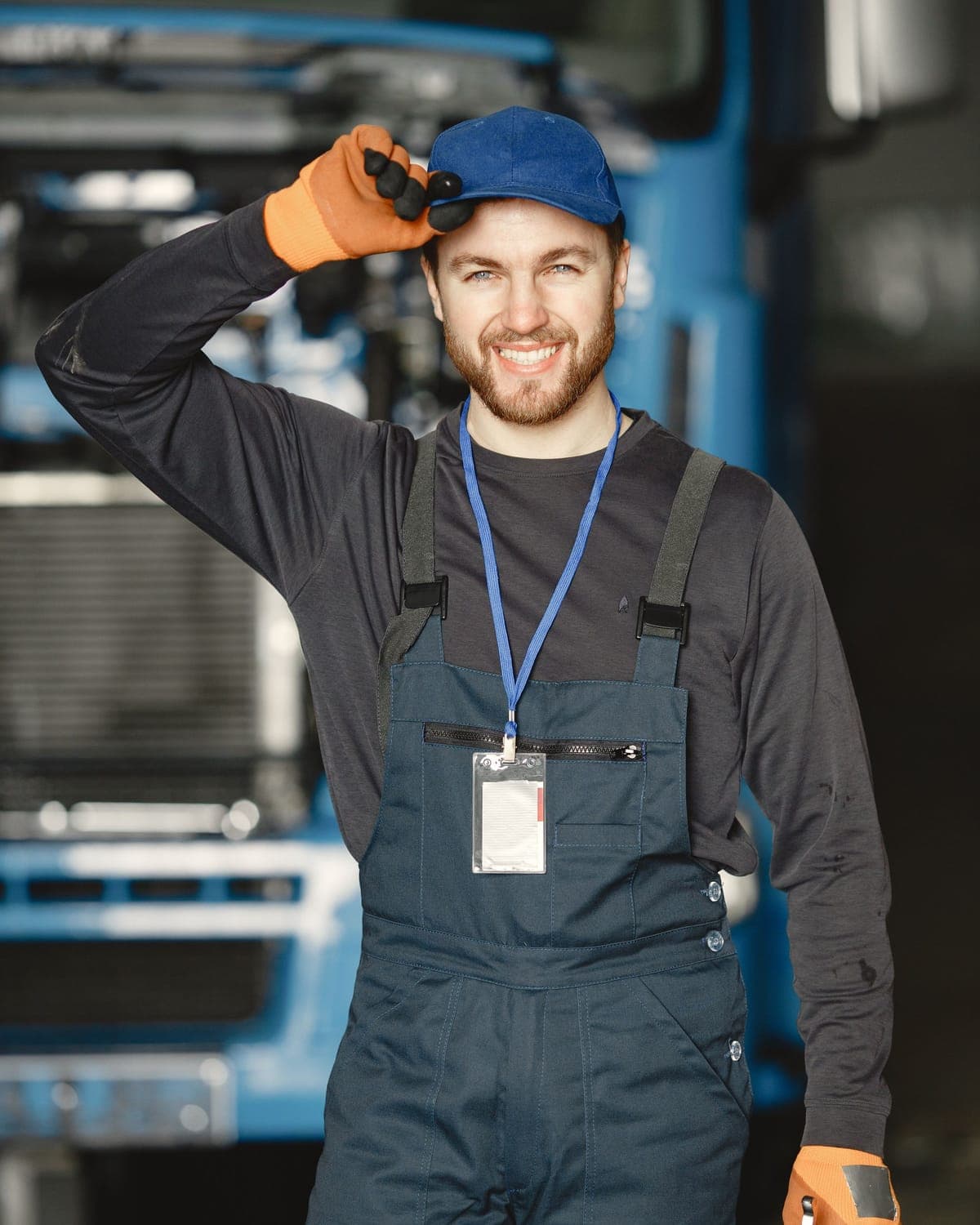 Un jeune garagiste souriant, casquette et salopette, salue