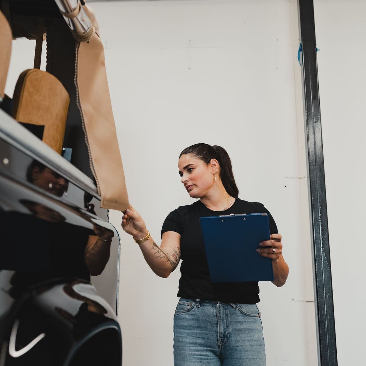 Une mécanicienne contrôle une voiture à l’atelier, porte-document en main