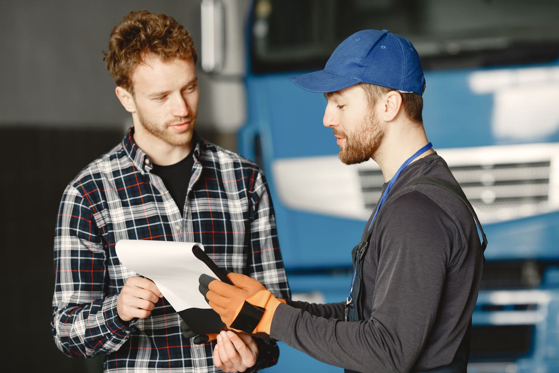 Mécanicien en tenue d’atelier présentant un document à un client dans un garage